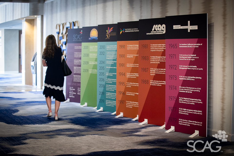 Person looking at colorful SCAG timeline panels in exhibit hallway.