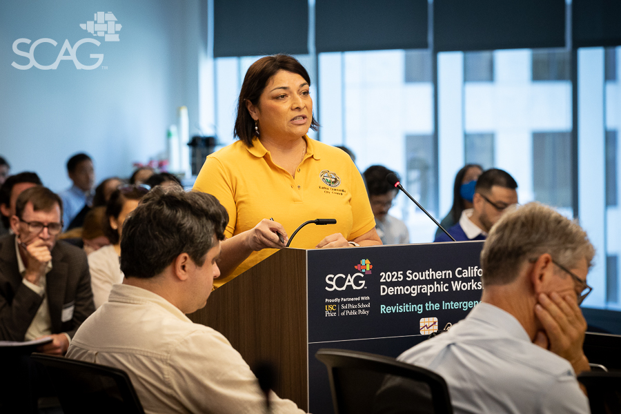 Speaker at a podium in a meeting room, wearing a yellow shirt.